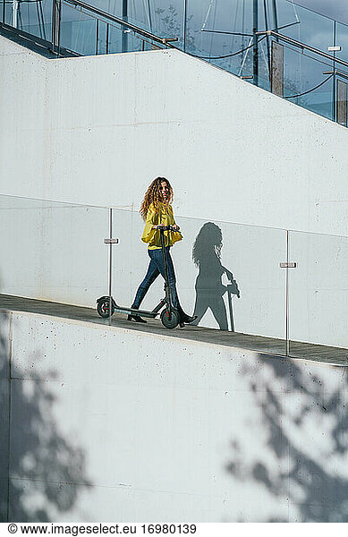 Woman with scooter walking on slope