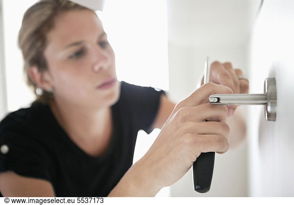 Woman with screwdriver fixing handle