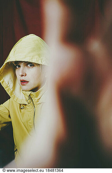 Woman with serious expression wearing yellow hoodie