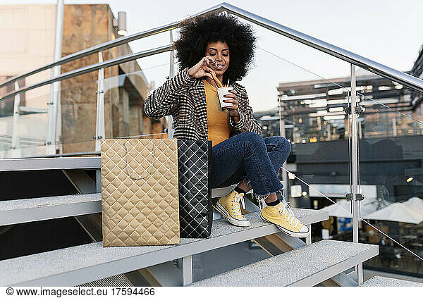Woman with shopping bags dipping churro in disposable cup