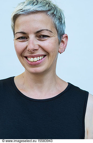 Woman with short grey hair wearing black top smiling at camera.