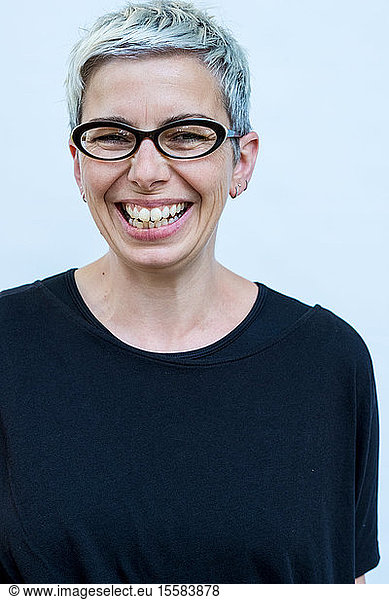 Woman with short grey hair wearing glasses smiling at camera.