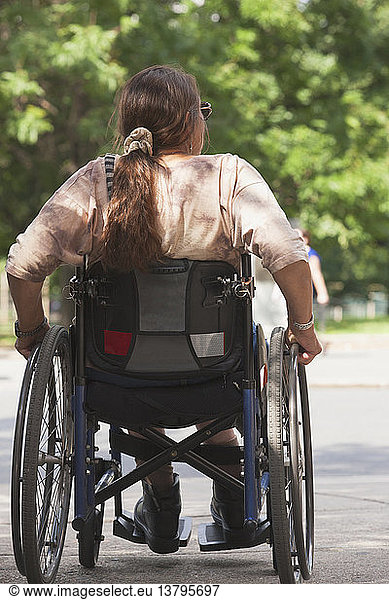Woman with spinal cord injury crossing street at accessible access  Boston  Massachusetts  USA