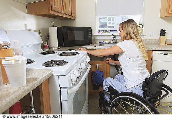 Woman with spinal cord injury preparing food in her accessible kitchen