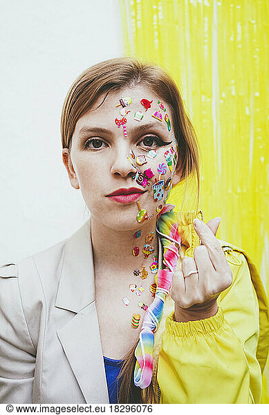 Woman with stickers on face gesturing heart shape