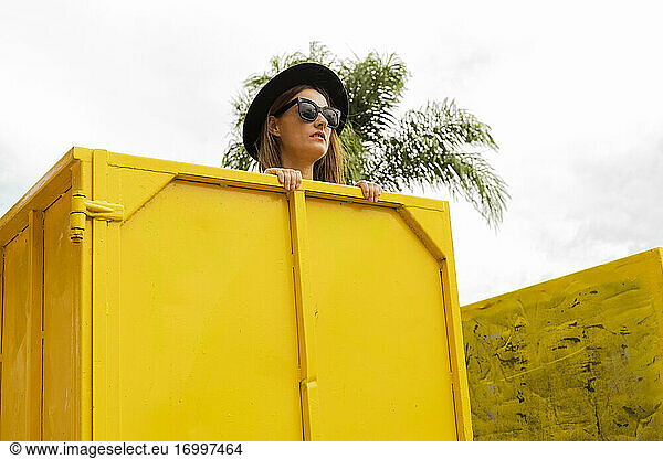 Woman with sunglasses  looking over edge of yellow container