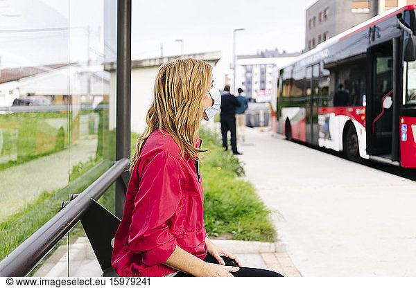 Woman with surgical mask at bus stop