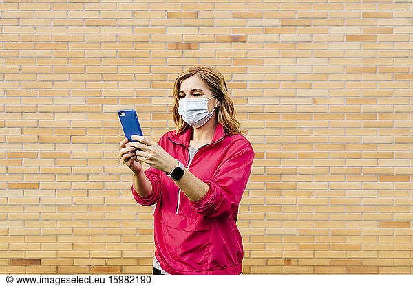 Woman with surgical mask using smartphone for video call