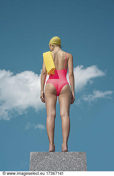Woman with swimming cap and swimsuit standing on column