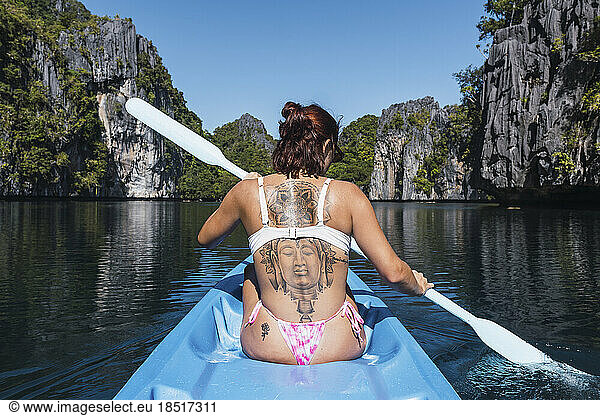 Woman with tattoo on back kayaking at sea