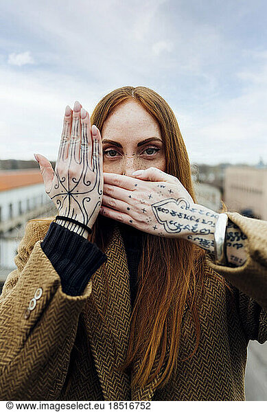 Woman with tattooed hand covering face