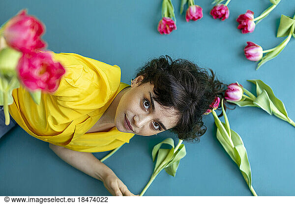 Woman with tulip flowers lying on green background