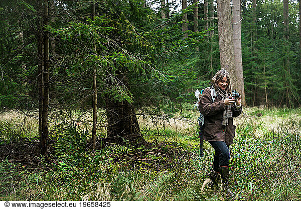 Woman With Vintage Camera Walking In Scandinavian Forest