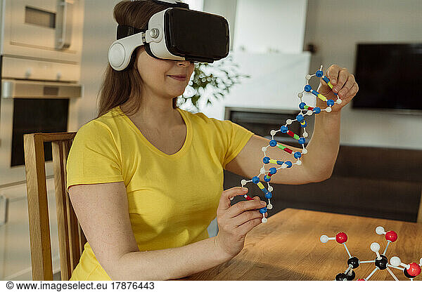 Woman with VR goggles examining helix model at home