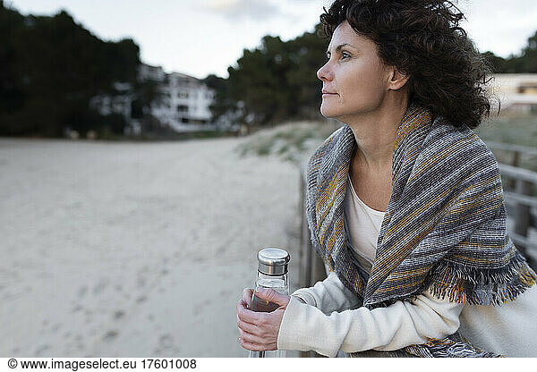 Woman with water bottle at beach in winter