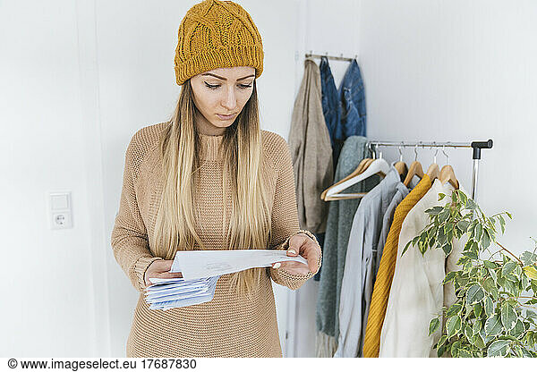 Woman with wooly checking bills standing in dressing room