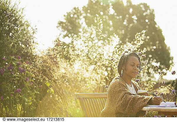 Woman working at sunny idyllic garden cafe table