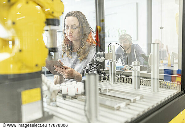 Woman working in robotic factory using digital tablet