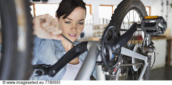 Woman working on bicycle in shop