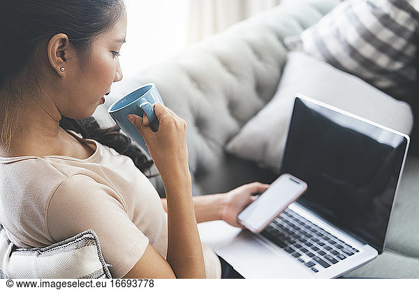 Woman working on laptop and drinking coffee.
