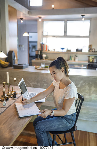 Woman working on laptop at dining table