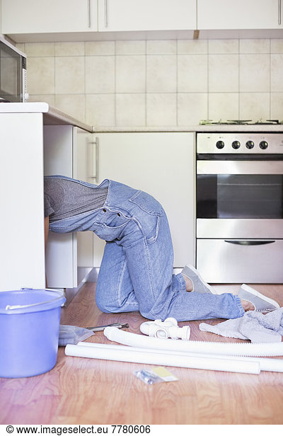 Woman working under kitchen sink