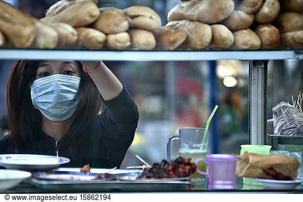 Woman works in the streets food business wearing anti-pollution mask