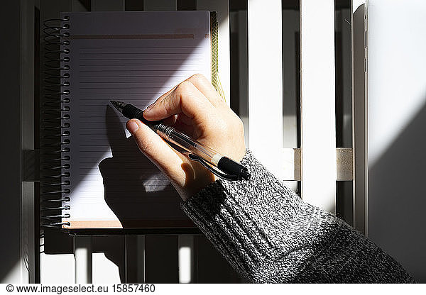 Woman writing on her calendar with a black pen.