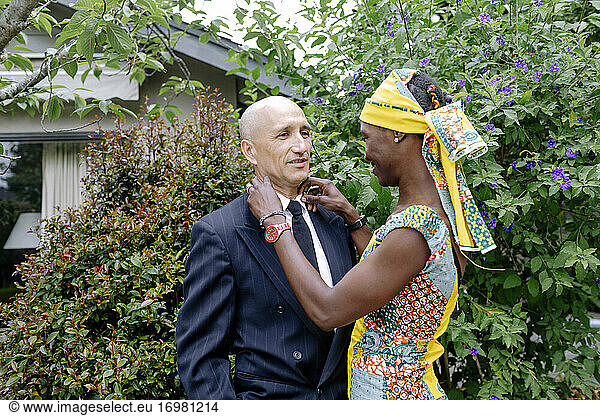 Womand dressing african attire helping husband adjusting tie