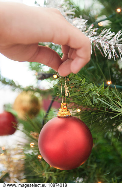 Womans hand hanging bauble on christmas tree