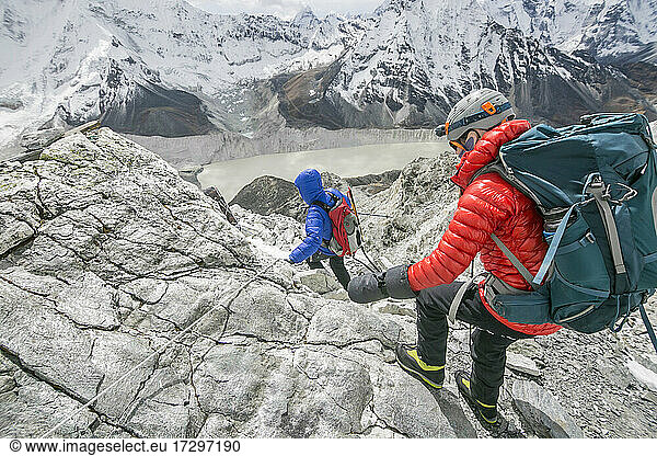 Women alpinists descending steep ridge terrain along a handline