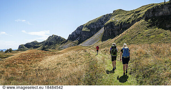 Women and man hiking towards Rifugio dal piaz on sunny day at Dolomites  Italy