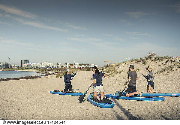 Women and man learning new things from male instructor at beach