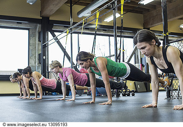 Women bending and exercising with resistance bands in gym