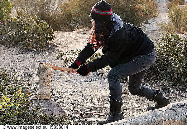 women chopping wood with axe in desert