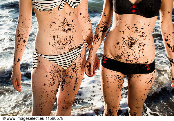 Women covered in sand on beach
