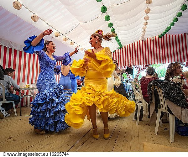 Women dancing Sevillano  Spanish woman with flamenco dresses in colourful marquee  Casetas  Feria de Abril  Sevilla  Andalusia  Spain  Europe