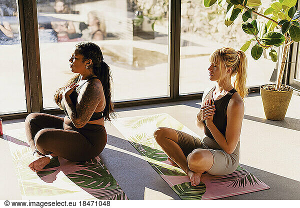 Women doing breathing exercise while sitting on exercise mats at retreat center