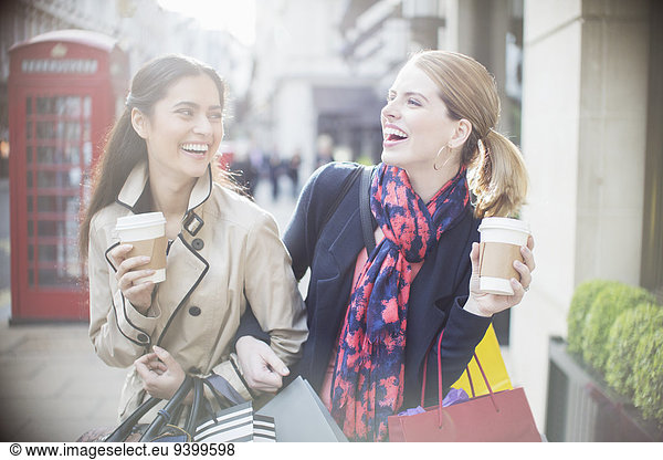 Women drinking coffee together on city street