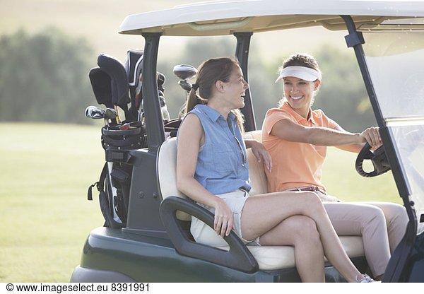Women driving cart on golf course