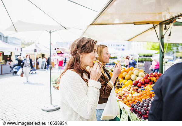Women eating fruit while shopping at market