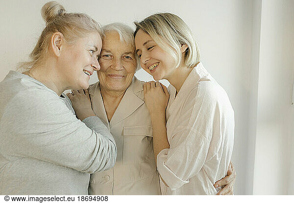 Women embracing grandmother at home