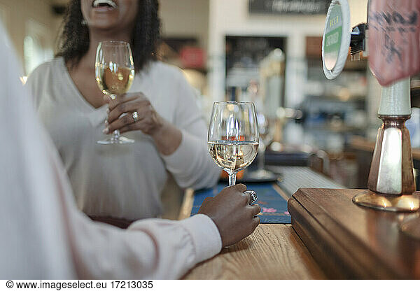 Women enjoying white wine at counter in pub