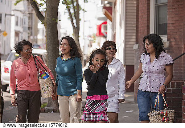 Women from three generations spend time together walking down a sidewalk