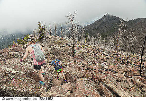 Women hike down South Boulder Peak  Colorado near burned trees