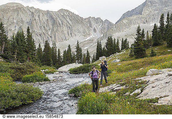 Women hike up creek  meadow to Pierre Lakes  Elk Mountains  Colorado