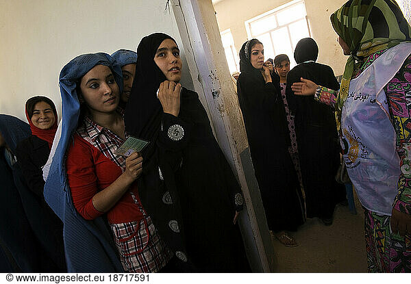 Women hold their registration cards as they wait in line to vote in the Sultan Razia Girls High School on the day of presidential and provincial elections in Mazar-i Sharif  Afghan