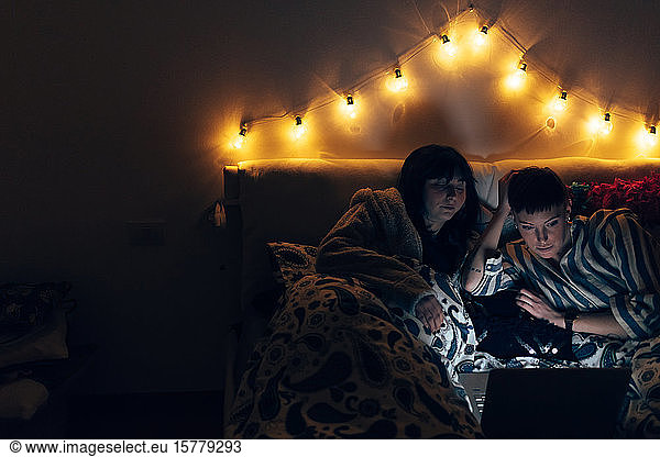 Women in bed in darkness using laptop