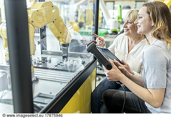 Women in factory using control of industrial robot