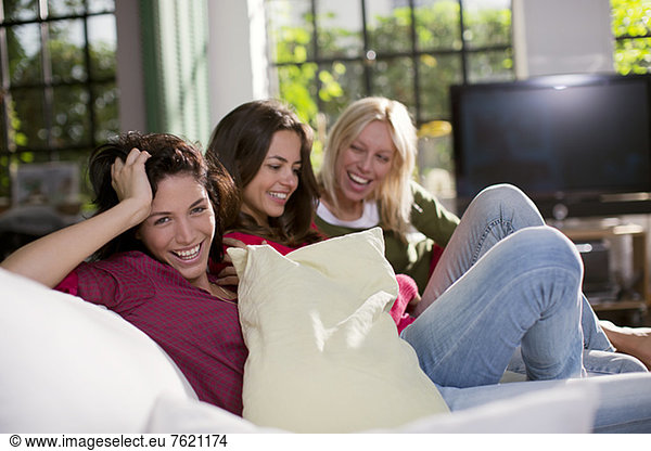Women laughing together on sofa
